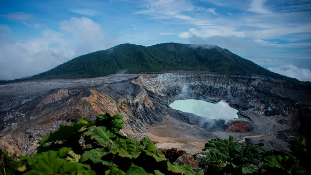 عکس از دهانه قله آتشفشان Poás که در مرکز آن دریاچه‌ای اسیدی به رنگ آبی قرار دارد