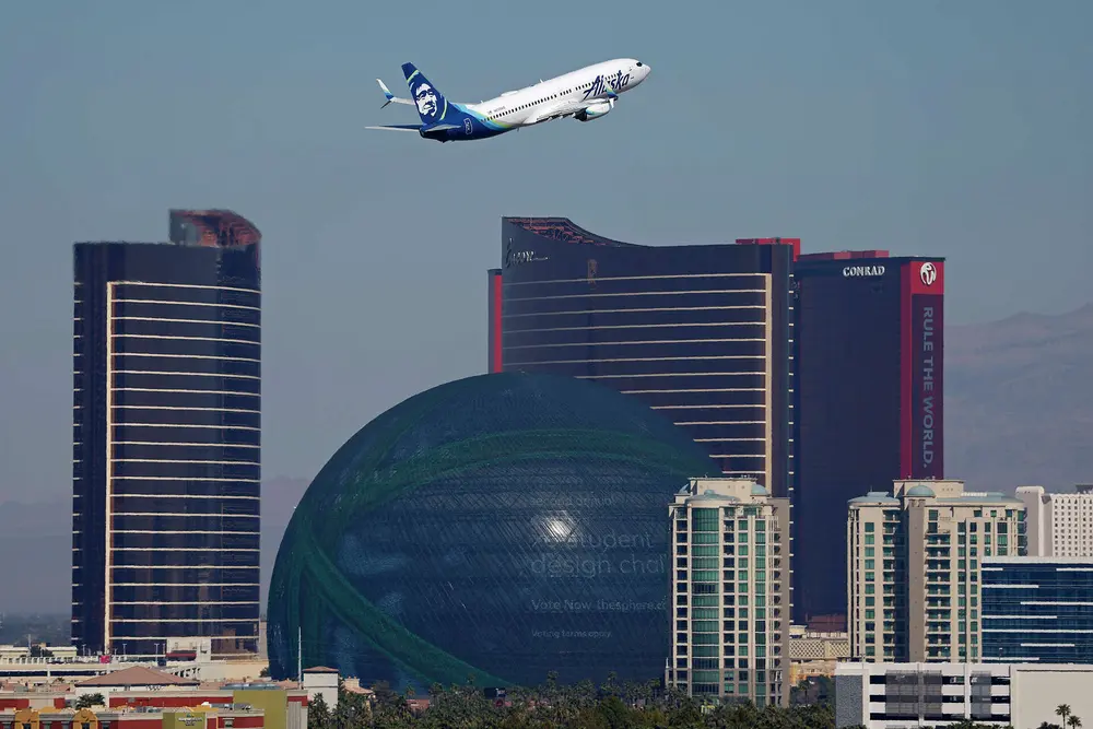 عکس: بوئینگ ۷۳۷ Alaska Airlines که از فرودگاه بین‌المللی هری رید در لاس‌وگاس پرواز می‌کند؛ هتل و کازینو Wynn و Encore و سازه Sphere در پس‌زمینه؛ ۱۵ مارس ۲۰۲۵.