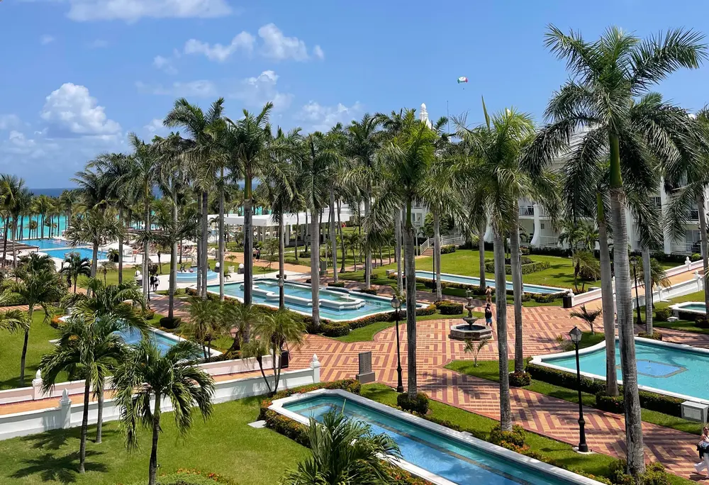 یک هتل تفریحی تمامپذیر با استخرها، فوارهها و درختان نخل.