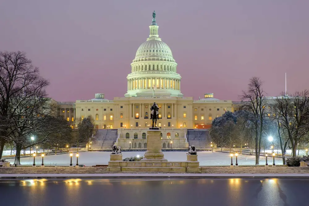 ساختمان کاپیتول ایالات متحده همراه با یک تندیس در پیش‌زمینه در هنگام غروب