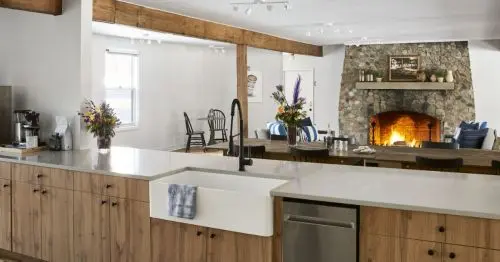 یک آشپزخانه و فضای غذاخوری با شومینه سنگی روشن.