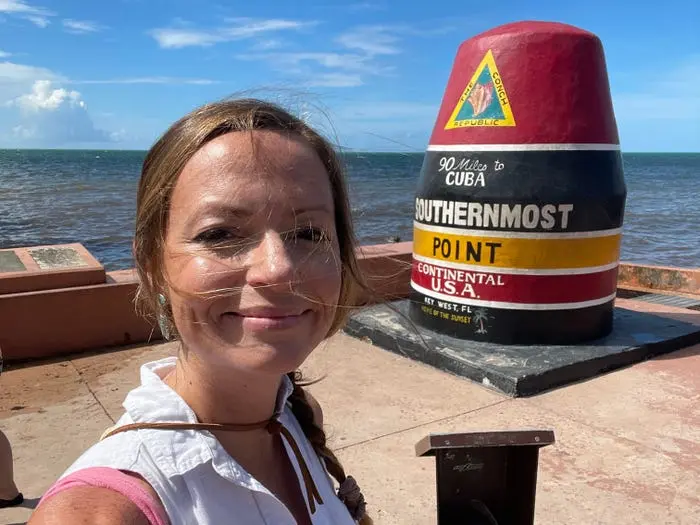 امیلی در حال سلفی گرفتن در مقابل نقطهٔ جنوبی‌ترین ایالات متحده در کی‌وست، فلوریدا، با پس‌زمینهٔ اقیانوس.