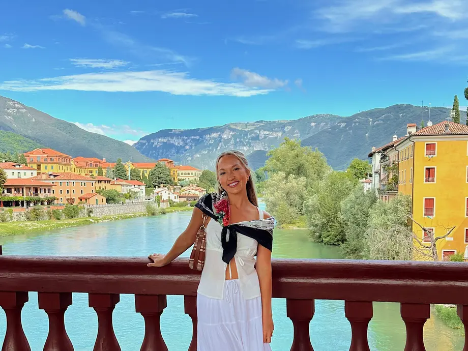 کلوی بر روی پلی در آب ایستاده است؛ پسزمینه شامل خانهها و کوههاست.