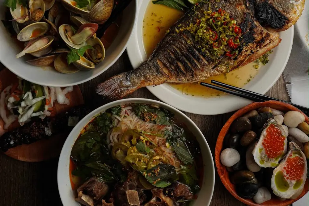 غذاهای مختلفی که روی میز چیده شده‌اند شامل ماهی کبابی، سوپ با سبزیجات و گوشت، صدف و صیطلان با تزئینات