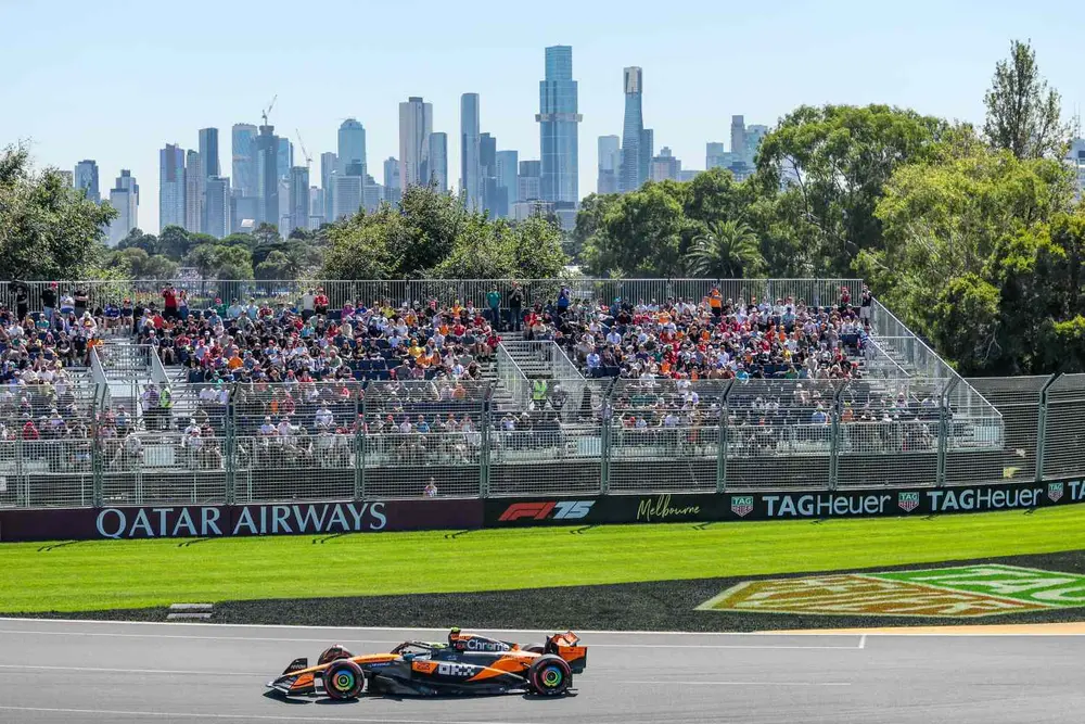 خودروی فرمول 1 در مسیر مسابقه می‌دود، نزدیک به جایگاه تماشاچیان پر از جمعیت و خط‌افق شهر در پس‌زمینه