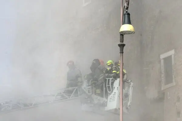 نیروهای امدادی در یک بالابر در میان گرد و غبار در کنار یک دیوار سنگی.