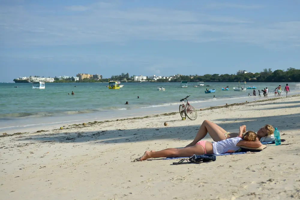 دو گردشگر در آفتاب بر روی ساحل استحمام می‌کنند