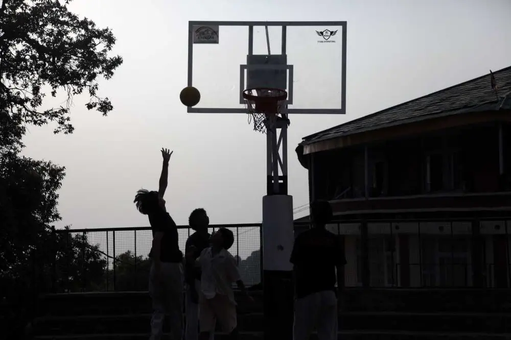 کودکان پس از مدرسه در محوطه مدرسه کودکان تبت در دارامشالا، شهری کوهستانی و مرتفع در هیمالیای شمالی هند که پایتخت غیررسمی تبتی‌های در تبعید است، بازی می‌کنند. تعداد کودکان این مدرسه در حال کاهش است که سرنوشت خود جامعه تبعیدی را بازتاب می‌دهد. عکس از ضیاء حدید، دارامشالا، آوریل ۲۰۲۵