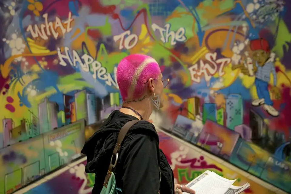 فان لی به اثر "بازگشت به آینده" توسط گرافیتی‌نویس ماندو "لِیس" مارتینز نگاه می‌کند؛ این اثر در مراسم افتتاح نمایشگاه "پیوستن قطعات: هنر گرافیتی آستین ۱۹۸۴ - ۲۰۰۴" در مرکز فرهنگی مکزیک-آمریکایی اِما اس. بارینتوس به نمایش درآمد. [جی جَنَر/امریکن-استیتسمَن]