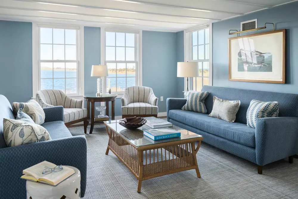 اتاق نشیمن با مبل‌ها، صندلی‌های راحتی و نمای ساحلی از طریق پنجره‌ها