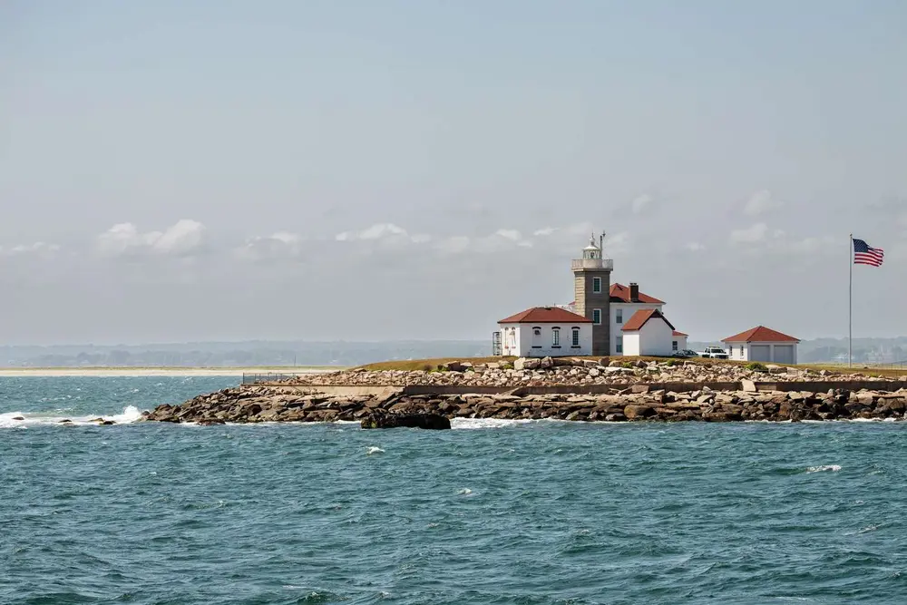 مجتمع فانوس دریایی در سواحل صخره‌ای، نزدیک به دریا، که پرچم آمریکا در کنار آن می‌لرزد
