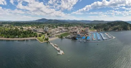 عکسی گسترده از شهری کنار دریاچه با کوه‌های پس‌زمینه و ابرهای فراگیر